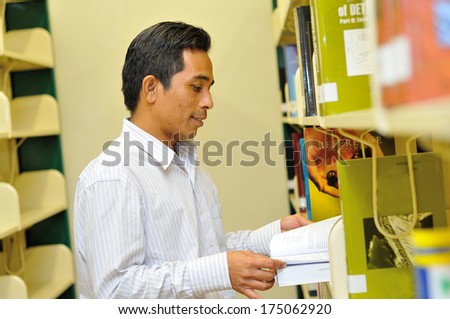 Male student browsing book at book shelf