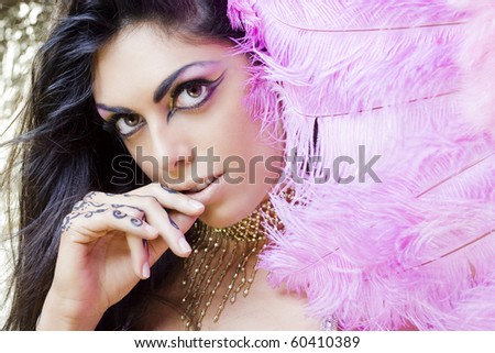 young beautiful dancer covering herself with a pink feather fan