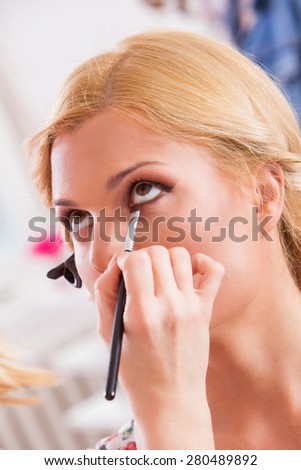 Professional Make-up artist doing beautiful girl makeup in studio