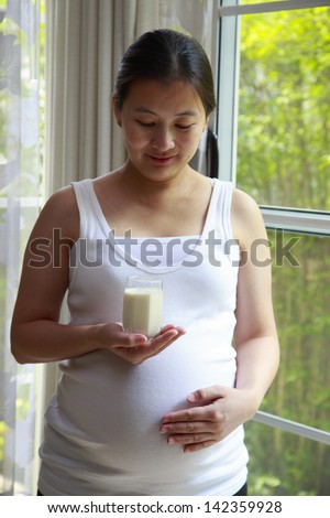 Young pregnant woman hold glass of milk on hand