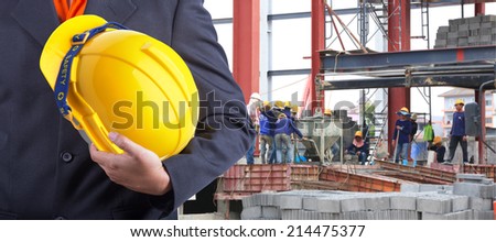 worker or engineer holding in hands yellow helmet for workers security on the background of a new building concrete floor with worker working hard
