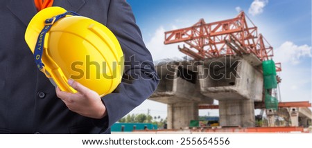 worker or engineer holding in hands yellow helmet for workers security on the background motorway construction with beautiful sky