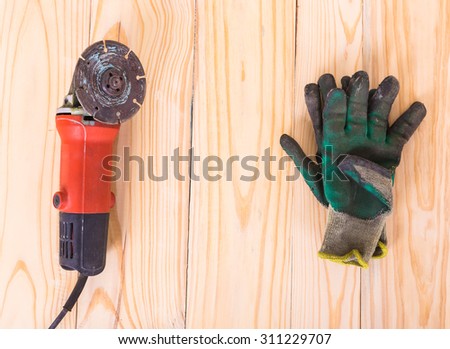the old grinder with used work glove on wood background