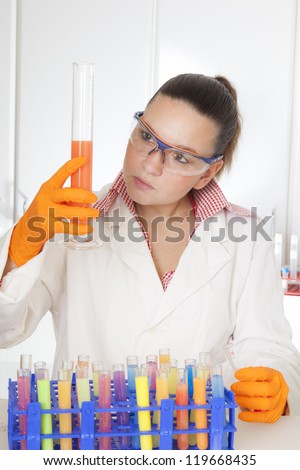 Cute medical or scientific researcher- chemist- scientist using a pipette and test tubes in a laboratory- selective focus