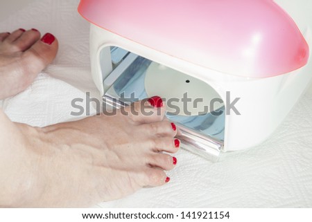 Drying in foot nail enamel drying device, Drying of enamel, series of STEP BY STEP nail varnishing process, HIGH RESOLUTION photos, Closeup, selective focus on nails