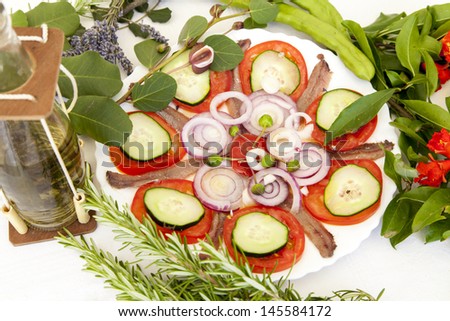 Sardine fillets on a white ceramic plate, served with various organic vegetables and decorated with Mediterranean herbs and Travarica rakia