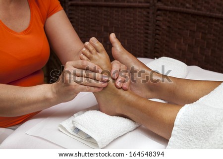 Woman receiving a leg and foot massage while lying on a towel in a awarded health massage center, series of various techniques