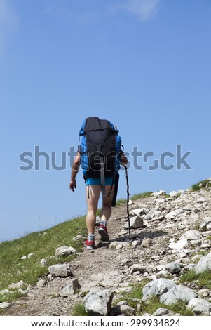 Paraglider,  trekker, mountaineer, walking up hill to a paragliding starting point, on a sunny morning, high in the mountains, space for text