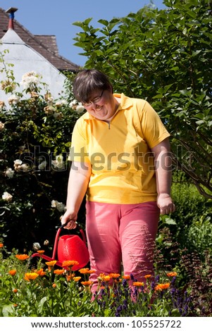 mentally disabled woman stands in the garden and  poured  flowers