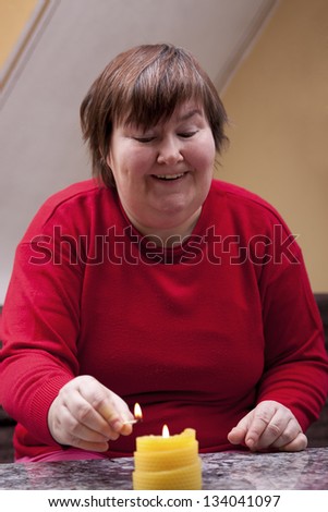 Mentally disabled woman lights a yellow candle