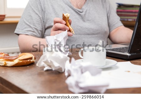 a untidy desk and a thick man with food in his hands