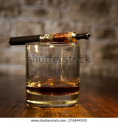 vintage still life with electronic cigarette and a glass of amber whiskey