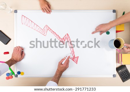 negative balance on whiteboard, overhead view with multiple hands