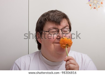 a sitting mentally disabled woman is smelling a flower