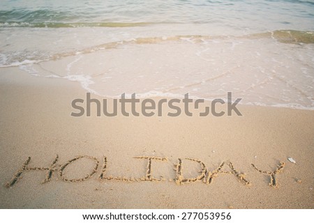 The word holiday written in sand on beach