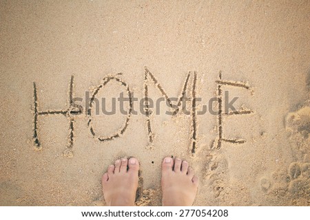 Selfie of word home written in sand on beach