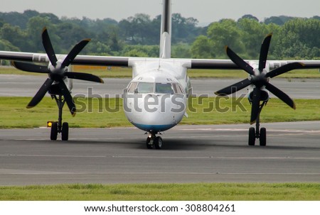 Manchester, United Kingdom - June 14, 2014: Flybe DHC-8 regional passenger plane at Manchester International Airport. Green vegetation on the background. Sunny weather.  Front view of the plane.