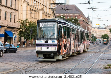 Helsinki, Finland - August 06, 2015: Modern tram driving in central Helsinki, Finland. Department stores and office buildings on the background.