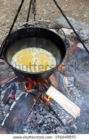 making food on camp fire, cooking in big metal cauldron