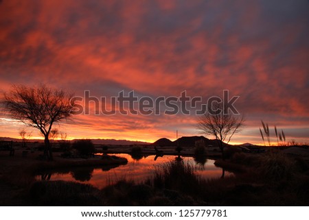 Red, blue, yellow colors of winter dawn clouds reflect in water/Red, White, Blue, Yellow Cloudscape Colors reflect in Water Landscape at Twilight/Colorful hues of winter cloudy sunup show in water