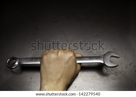 wrench in a hand on the dark surface