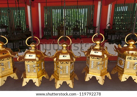 Row of beautiful gold lanterns hanging from the roof of a Japanese temple