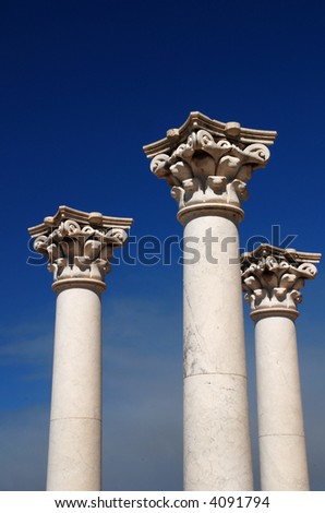 Three ancient greek pillars against a blue sky