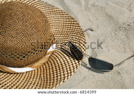 Hat and sun glasses are laying on the beach