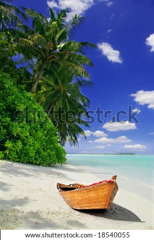 Tropical Maldivian beach with palms and wooden fishing ship