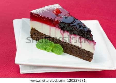A piece of forest fruit cake on a square plate and red tablecloth