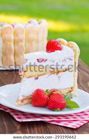 Delicious strawberry cream cake Charlotte on a wooden background
