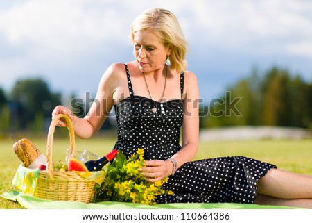 Alone woman with a picnic basket sitting on the blanket