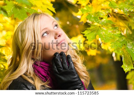 Beautiful girl face poses on a park, autumn color leaves on the background, horizon format