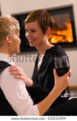 A portrait of a lesbian couple in love, fireplace on background, vertical format