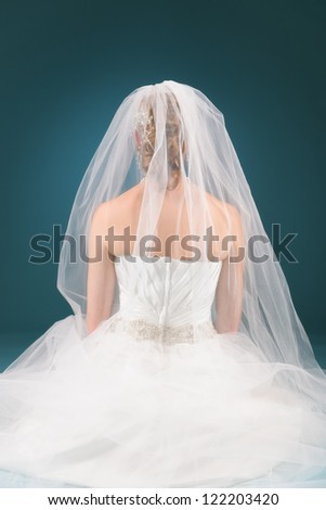 Beautiful bride praying alone, blue background, vertical format