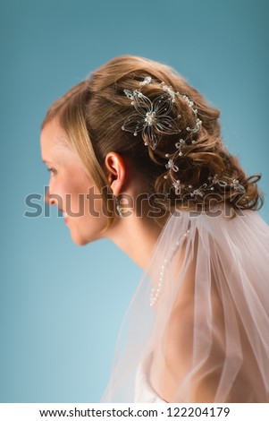 Bride have a beautiful decoration on a hair, blue background and vertical format