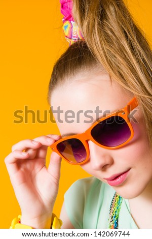 Beautiful girl wearing sunglasses, yellow background, vertical format