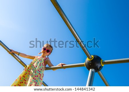Young girl on the jungle gym, sunny day