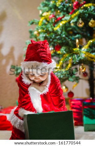 Boy opens a Christmas gift box, Christmas tree and gifts on background