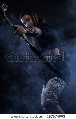 Beautiful archery woman aiming, smoky background