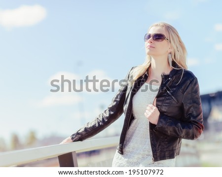 Fashionable beautiful young blond wearing a leather jacket, warm sunny day