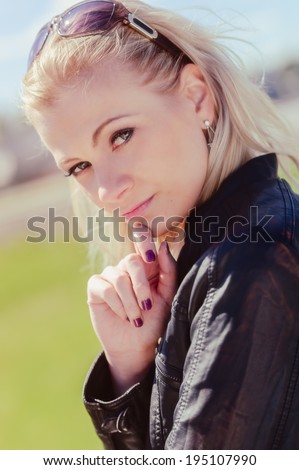 Close up, fashionable beautiful young blond wearing a leather jacket, warm sunny day