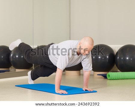 Mature man takes care of his health, he exercise pilates and stretching in a gym