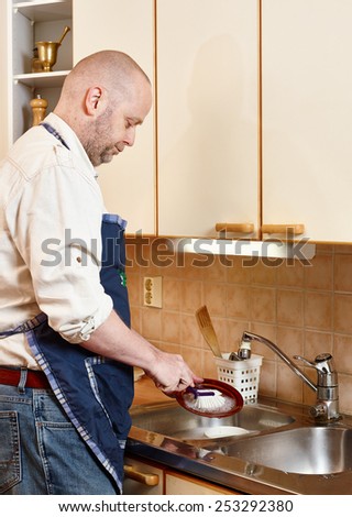 Homeworks, serious man washes dishes by hand