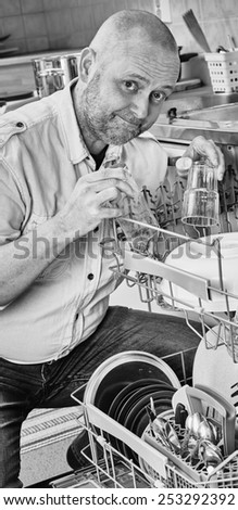 Homeworks, smiling man to fill the dishwasher, black and white image