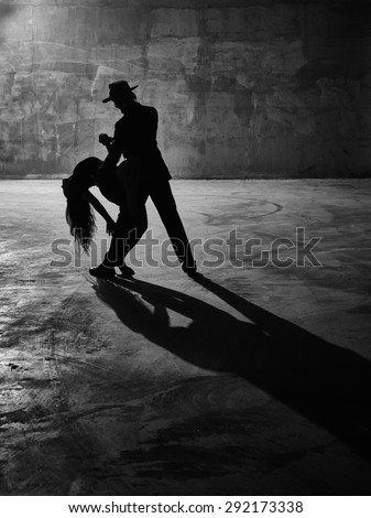 Man and woman dancing, urban dancing theme, concrete building surroundings, black and white image