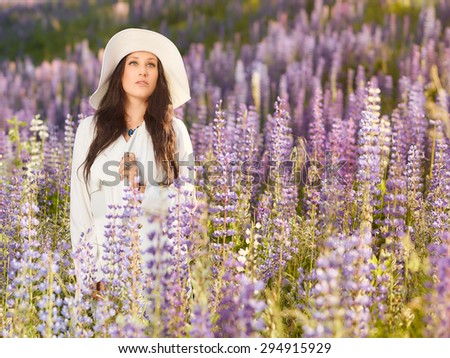 Fashionable young woman wearing a white hat and jacket, summery meadow