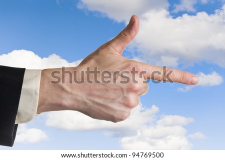 Mans hand, pointing index finger, cloudy blue sky background.