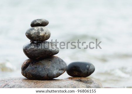 Rounded stones are set-up to pile, focus on stones, sea on the background.
