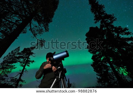 One night man watching northern sky, aurora behind.